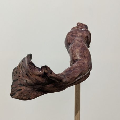 Holzskulptur mit geschwungenen Formen und detailreicher Maserung auf einem Ständer.
