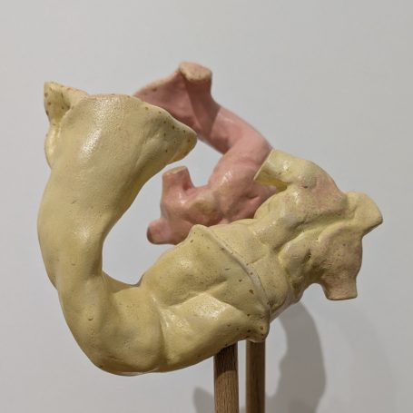 Abstrakte Skulptur in Beige und Rosa, die menschliche Formen darstellt.