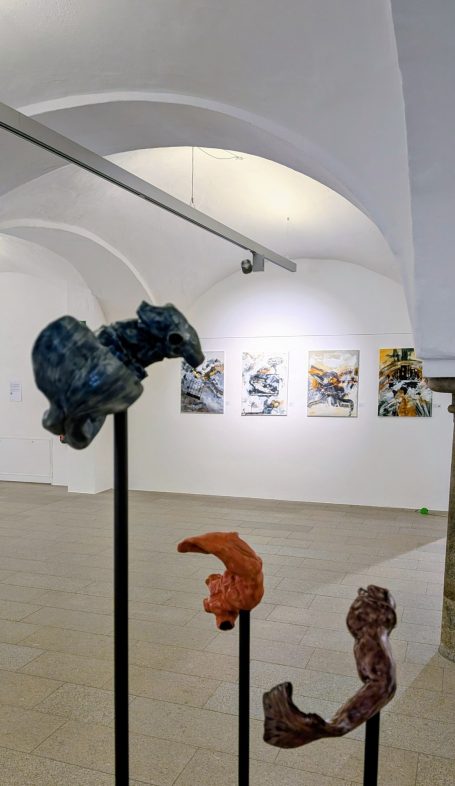 Drei abstrakte Skulpturen auf Ständern in einem weißen Ausstellungsraum.
